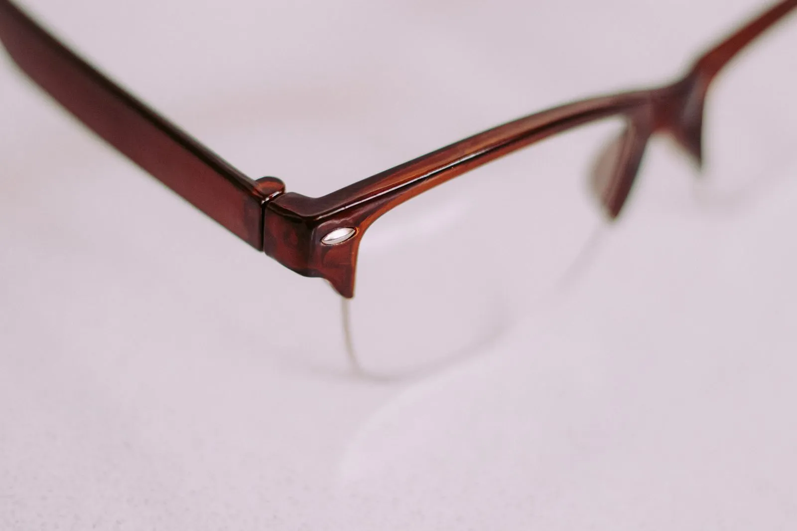 A detailed artistic close-up of a brown vintage style eyeglasses frame with a focus on the corner.